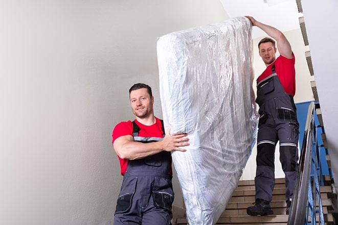 two workers carrying a heavy box spring out of a bedroom in Eddyville