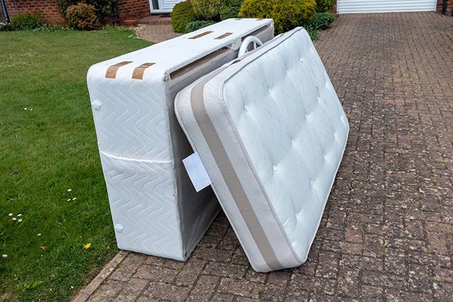 two people disposing of a worn-out mattress